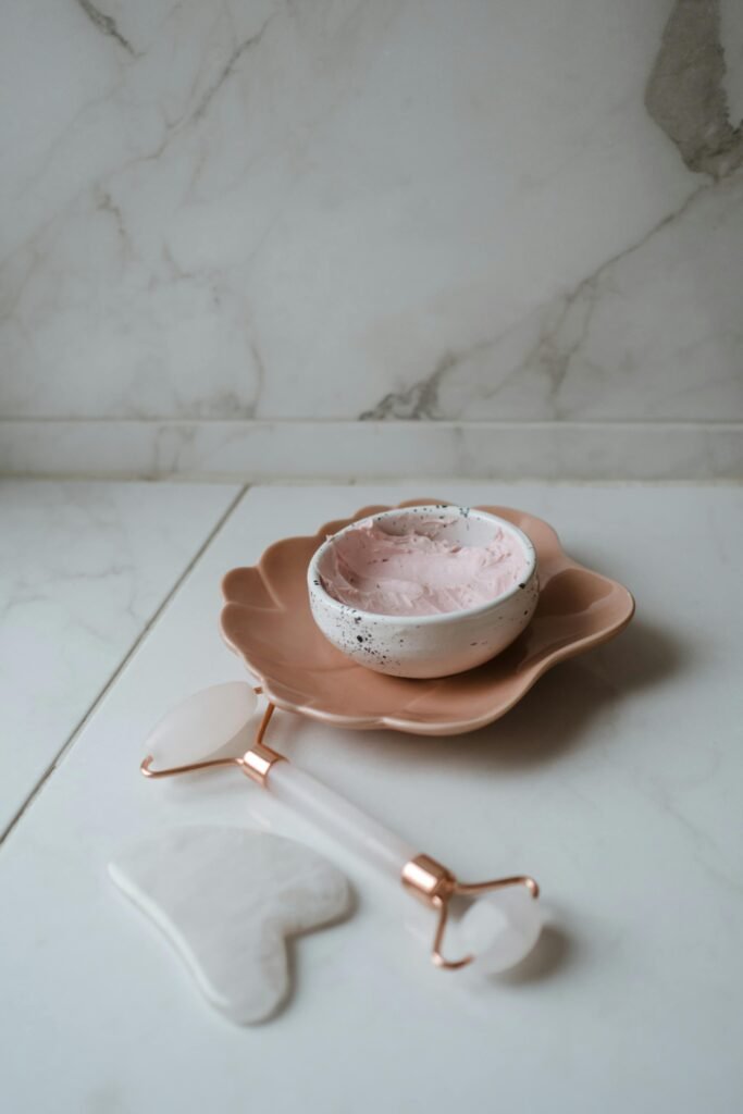 Aesthetic arrangement of skincare tools and cream on a marble surface enhancing beauty routines.